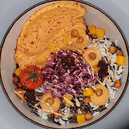 Frische Bowl mit Reis, Hummus, Rotkohlsalat, Kichererbsen, Tomate und Gemüse.