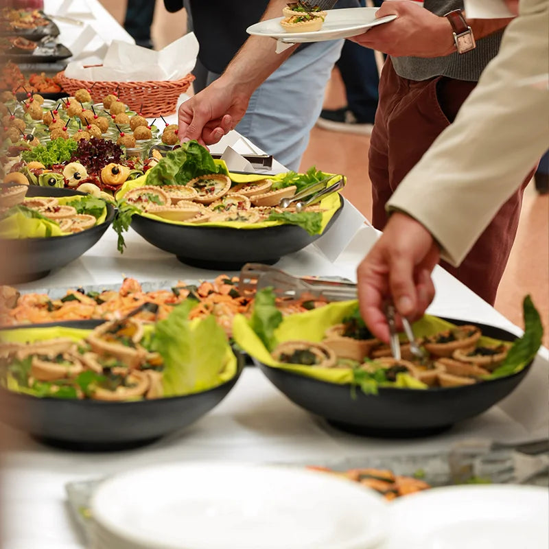 Teilnehmende bedienen sich bei einer Tagung an einem vielseitigen Fingerfood-Buffet