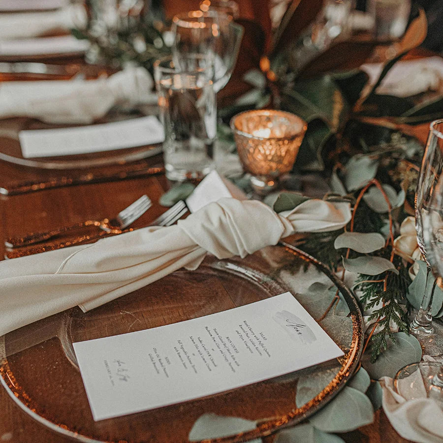 Festlich gedeckte Hochzeitstafel mit Menükarte, Kerzen und floraler Dekoration