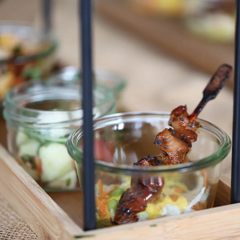 Fingerfood im Glas mit glasiertem Spieß für Gäste am Messestand