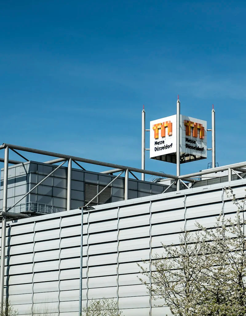 Außenansicht der Messe Düsseldorf in Stockum mit dem Logo auf dem Hallendach