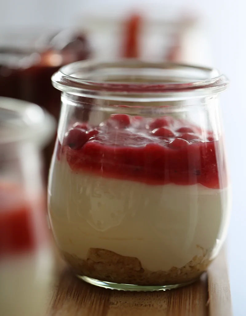 Dessert im Glas mit rotem Fruchtcoulis und Keksboden
