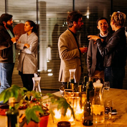 Gäste unterhalten sich bei einem abendlichen Business-Event mit Getränken und kleinen Speisen.